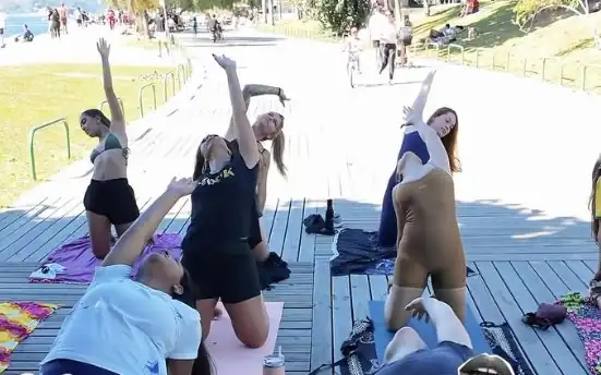 Grupo de mulheres alongando juntas sobre tapetes em um deck à beira-mar